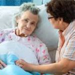 Older woman in hospital bed with younger woman sitting next to her