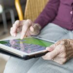 Older woman playing solitaire on an ipad, face is not visible.