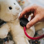 Hand holding stethoscope on a teddy bear's chest